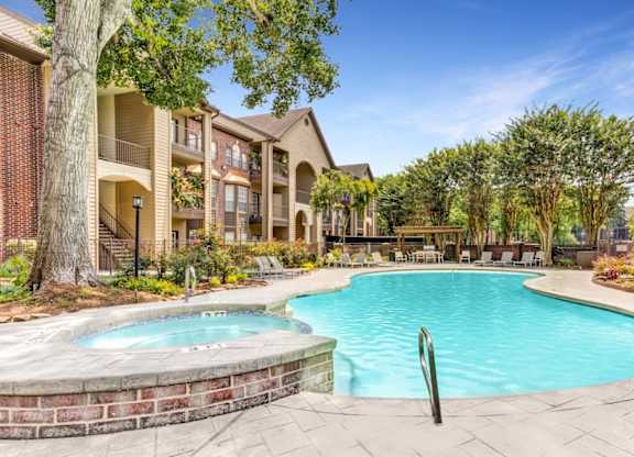 A swimming pool surrounded by a brick wall and trees.