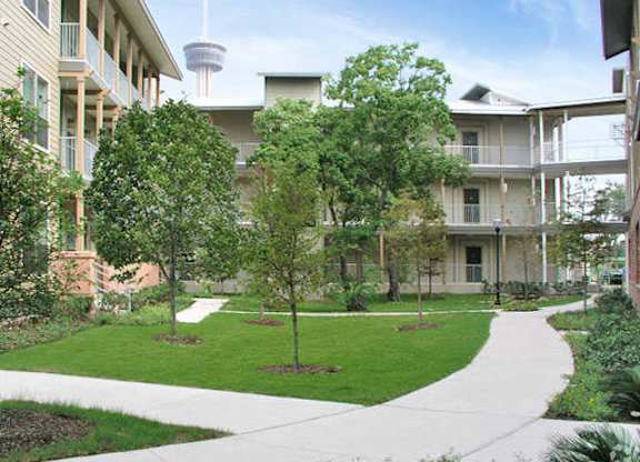 the courtyard of an apartment building with trees and a sidewalk