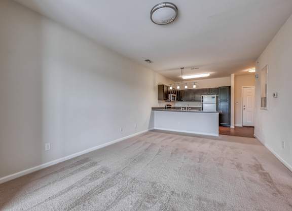 A spacious living room with a kitchen in the background.