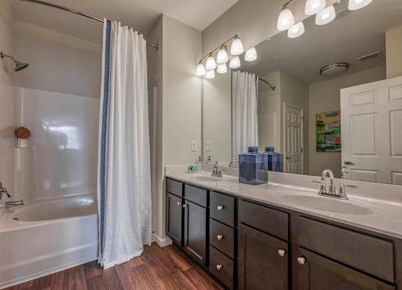 A bathroom with a white tub, sink, and shower curtain.