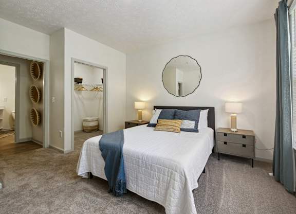 A bedroom with a bed, nightstands, and a mirror.