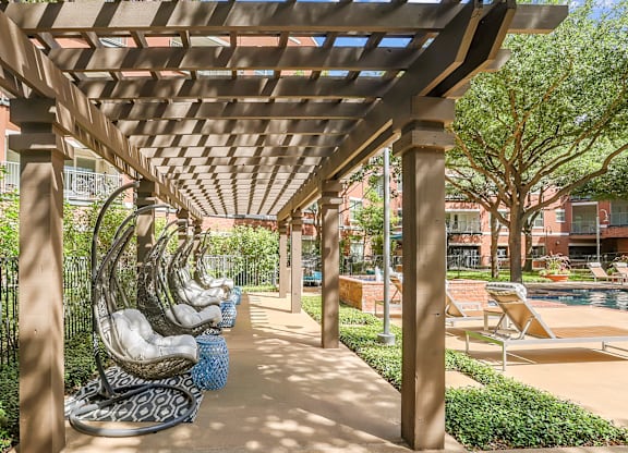 A row of concrete statues are lined up under a wooden pergola.