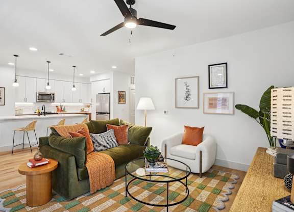 A living room with a green couch and a fan on the ceiling.