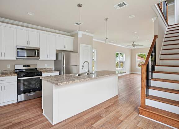 A kitchen with white cabinets and a wooden floor.