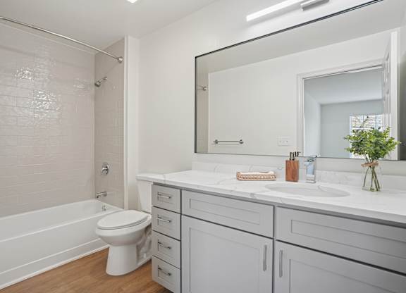 A white bathroom with a toilet, sink, and mirror.