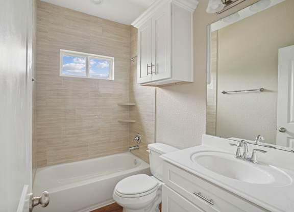 A white bathroom with a tub, toilet, and sink.