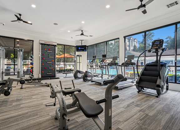 A gym with a variety of equipment including treadmills, weights, and exercise machines.