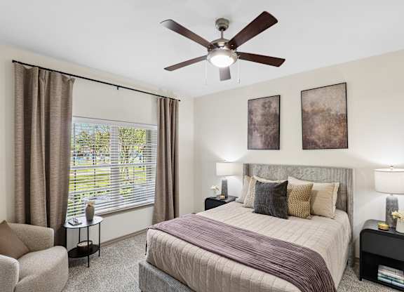 A bedroom with a bed, chair, and window.
