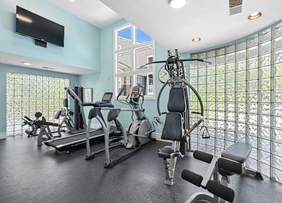 A gym with a row of treadmills and exercise bikes.