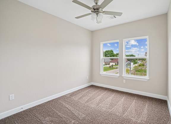 A room with a ceiling fan and two windows.