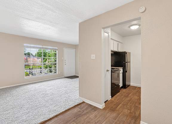 A kitchen area with a refrigerator and oven in a room with a window.