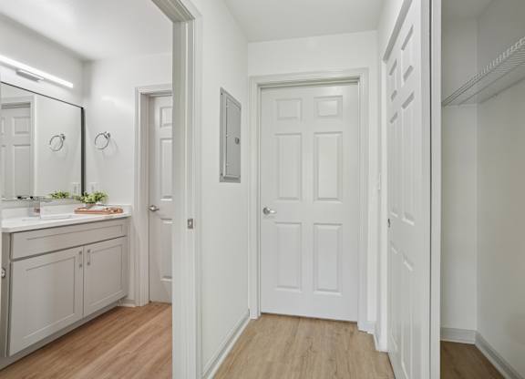 A white door is in a hallway with a mirror on the wall.
