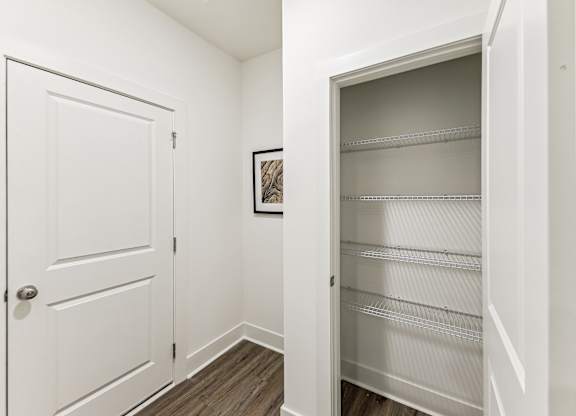 an empty closet with a white door and a door to a white closet with shelves
