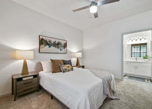 A bedroom with a bed, nightstand, and a painting on the wall.