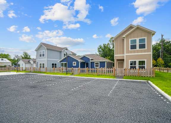 A house with a blue roof is situated in a gravel lot.