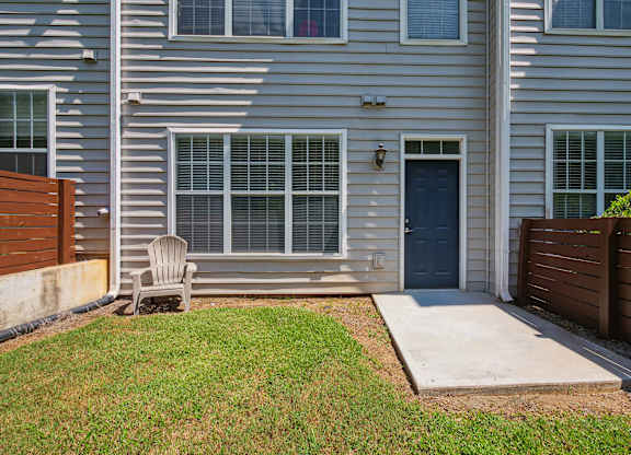 A grey house with a blue door and a wooden fence.