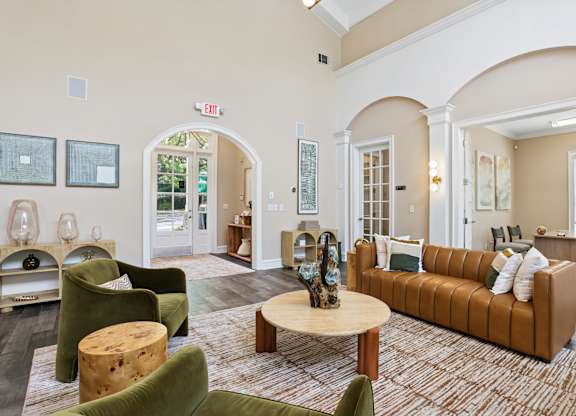 A living room with a brown couch and green chairs.