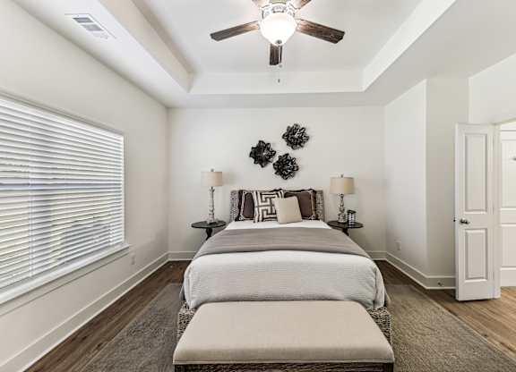 A bedroom with a bed, two lamps, and a ceiling fan.