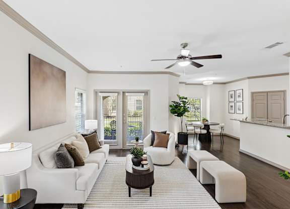 A living room with a white couch and a painting on the wall.