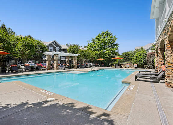 A large outdoor swimming pool surrounded by lounge chairs and umbrellas.