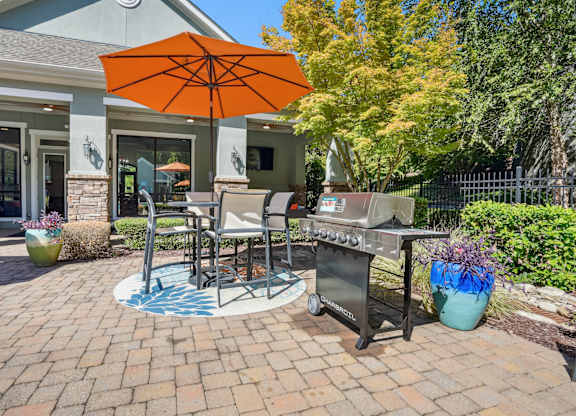 A patio with a table, chairs, and an umbrella.