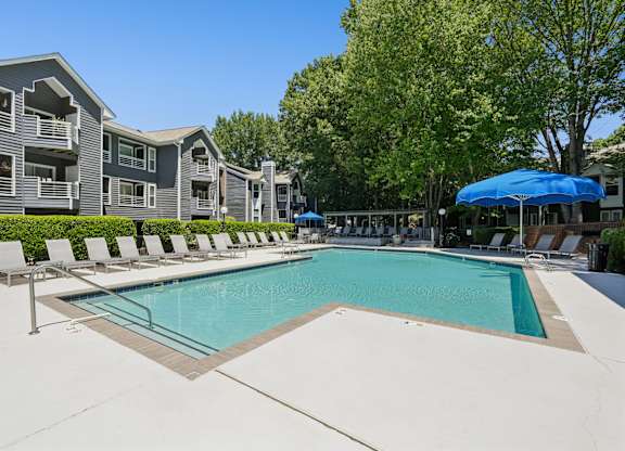 A large swimming pool surrounded by lounge chairs and umbrellas.