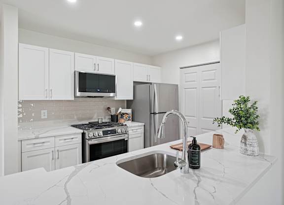 A kitchen with white cabinets and a marble countertop.
