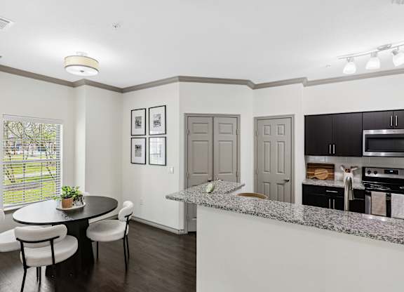 A kitchen with a table and chairs in the foreground and a countertop with a plant on it.