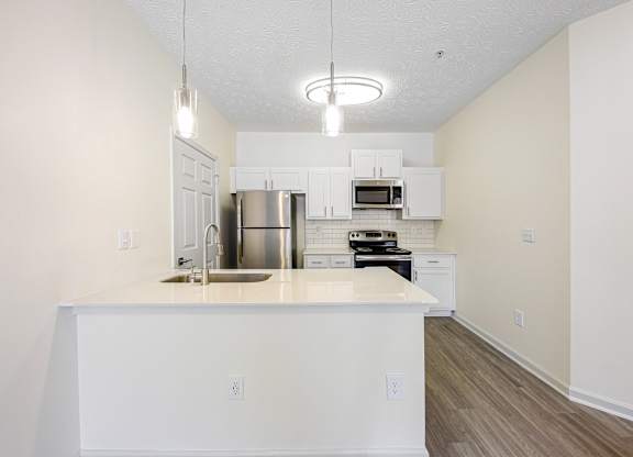 A kitchen with white cabinets and a white island.