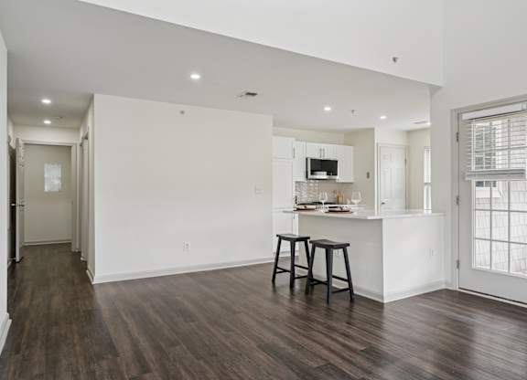 A kitchen with white walls and a wooden floor.
