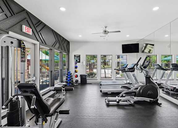 A gym with a row of treadmills and elliptical machines.