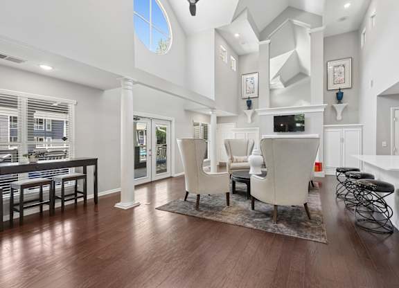 A modern living room with a large window and a kitchen area in the background.