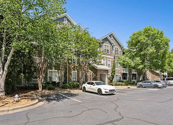 A white car is parked in front of a building with a tree in front of it.