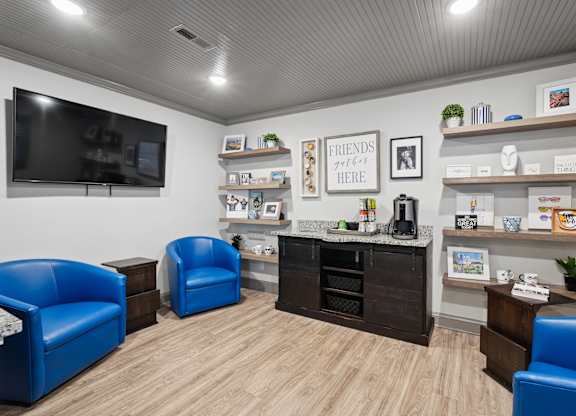 A waiting room with blue chairs and a flat screen TV.