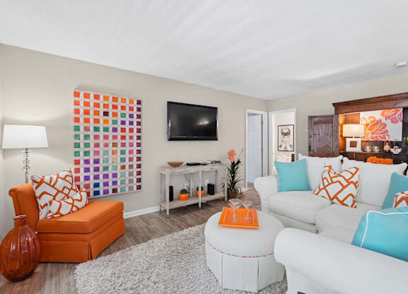 A living room with a white couch and orange accents.