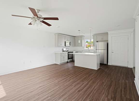 A kitchen with a ceiling fan and wooden floors.