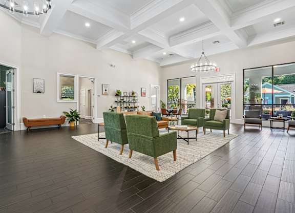 A spacious living room with dark wood floors and green chairs.