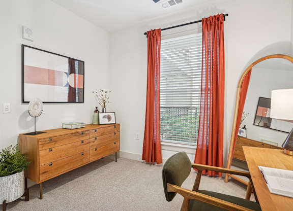 A room with a dresser, chair, and a painting on the wall.
