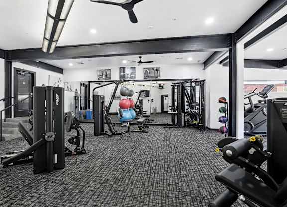 A black and white photo of a gym with a variety of equipment.