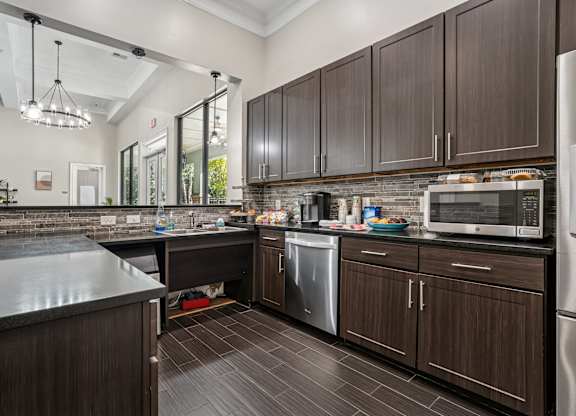 A kitchen with dark wood cabinets and a black counter top.