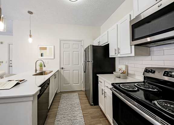 A kitchen with black appliances and white cabinets.