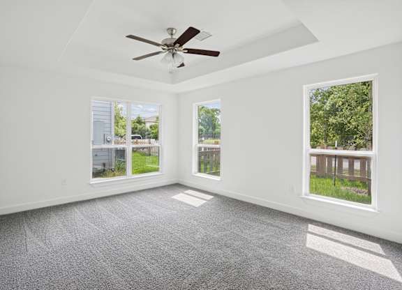 A room with a ceiling fan and two windows.