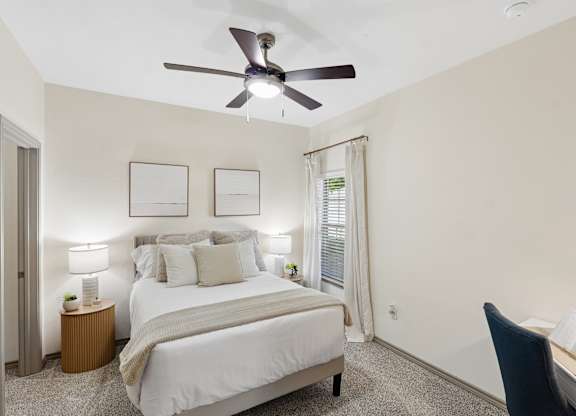 A bedroom with a bed, desk, and chair.