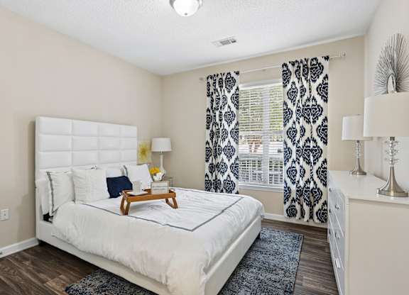 A bedroom with a white bed and a wooden tray on it.