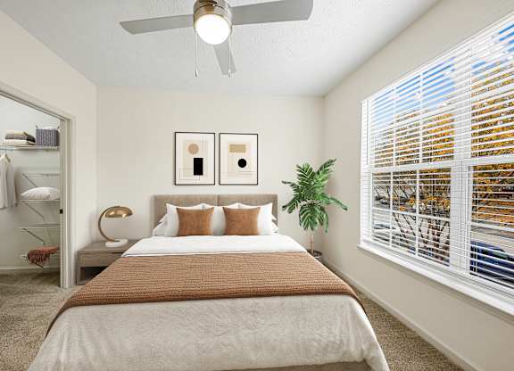 A bedroom with a bed, a ceiling fan, and a window with blinds.