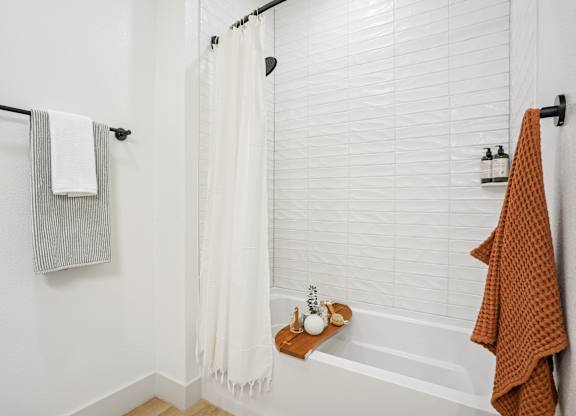 A white bathroom with a white tub and a white shower curtain.