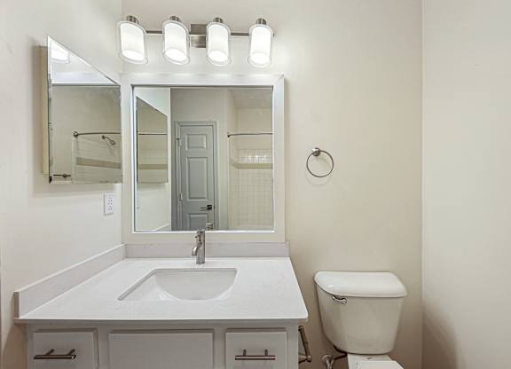 A white bathroom with a sink, toilet, and mirror.