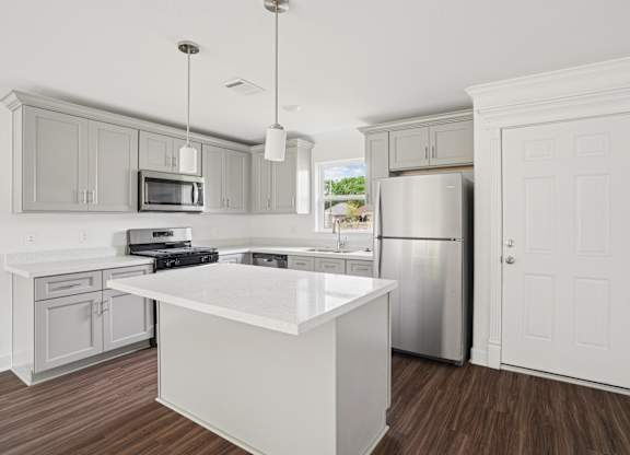 A kitchen with a white island and stainless steel appliances.