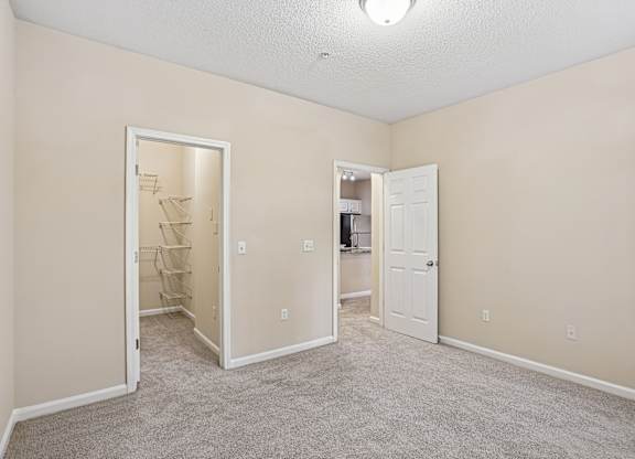 A room with a carpeted floor and two open doors.