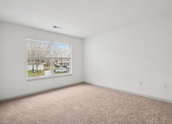 A room with a window and a carpet on the floor.